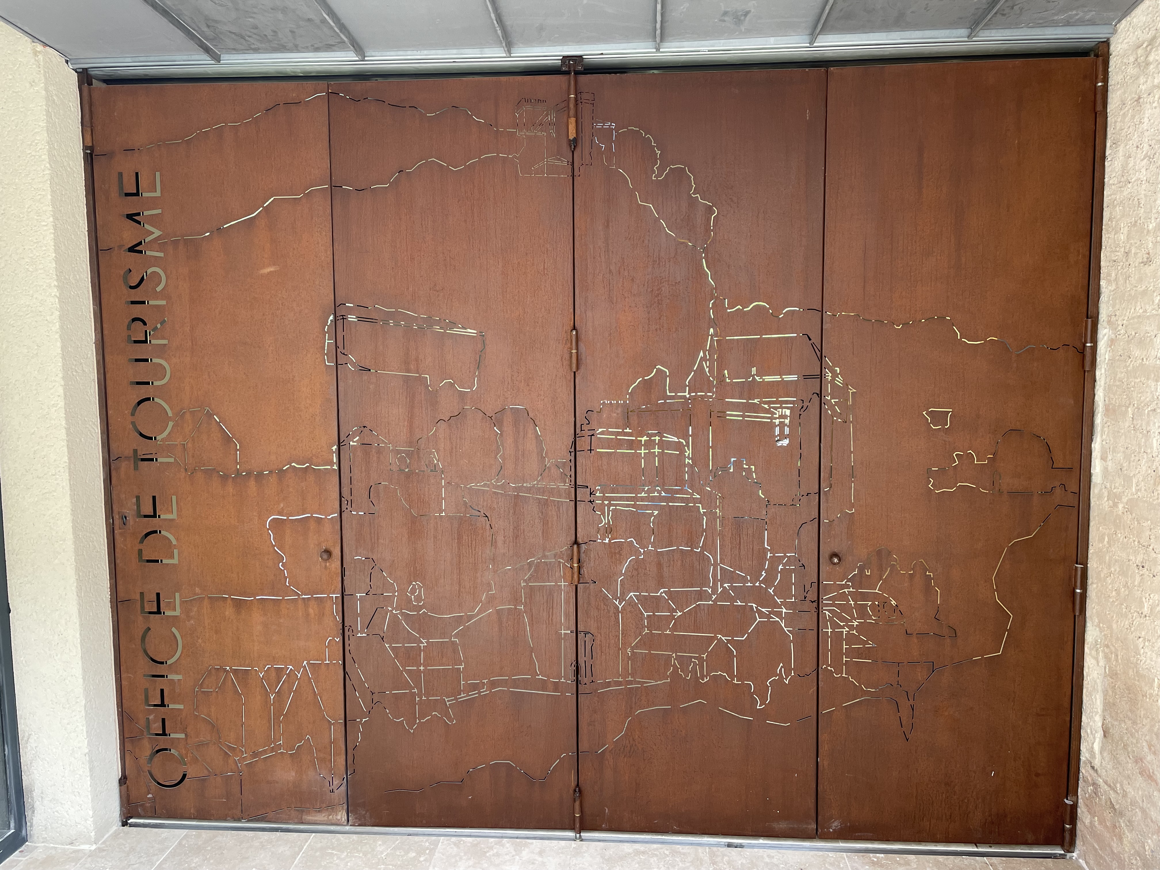 Portes d'entrée en métal corten : Les portes ajourées représentant une cartographie stylisée de Rocamadour, signées "Office de Tourisme"